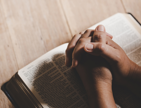 Un hombre con las manos sobre la biblia aprendiendo a usar aplicaciones para leer la biblia